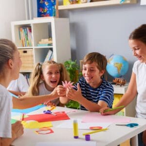 A group of children sitting at a table with paper.