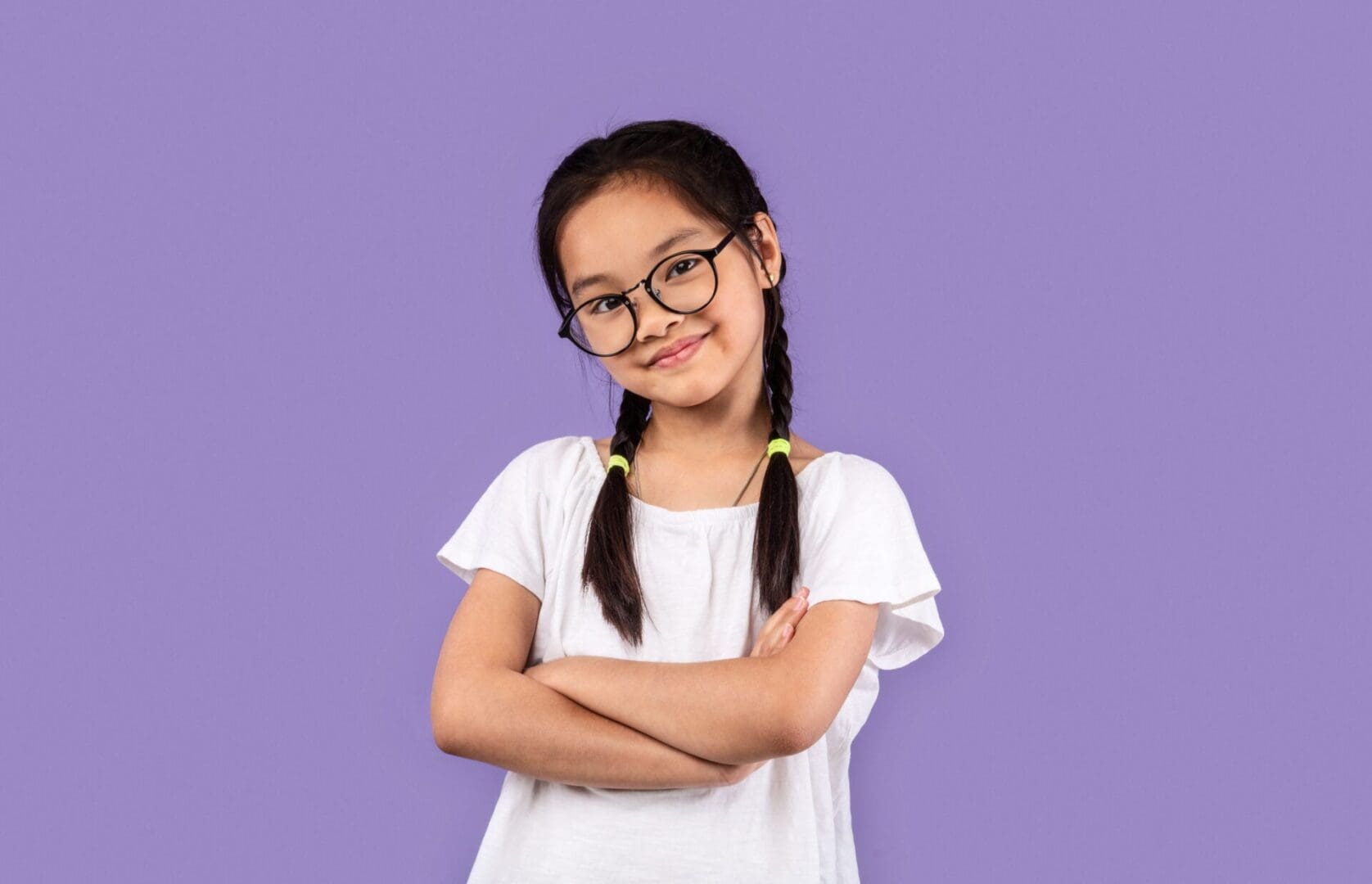 A girl with glasses and pigtails posing for the camera.