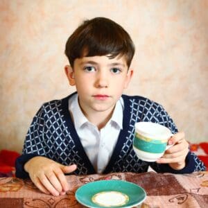 A boy sitting at the table with a bowl of cereal.